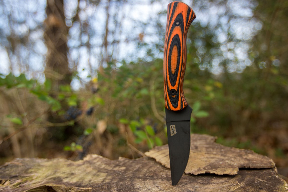 The Montana Knife Company Blackfoot 2.0 stuck in a stump in front of brush.