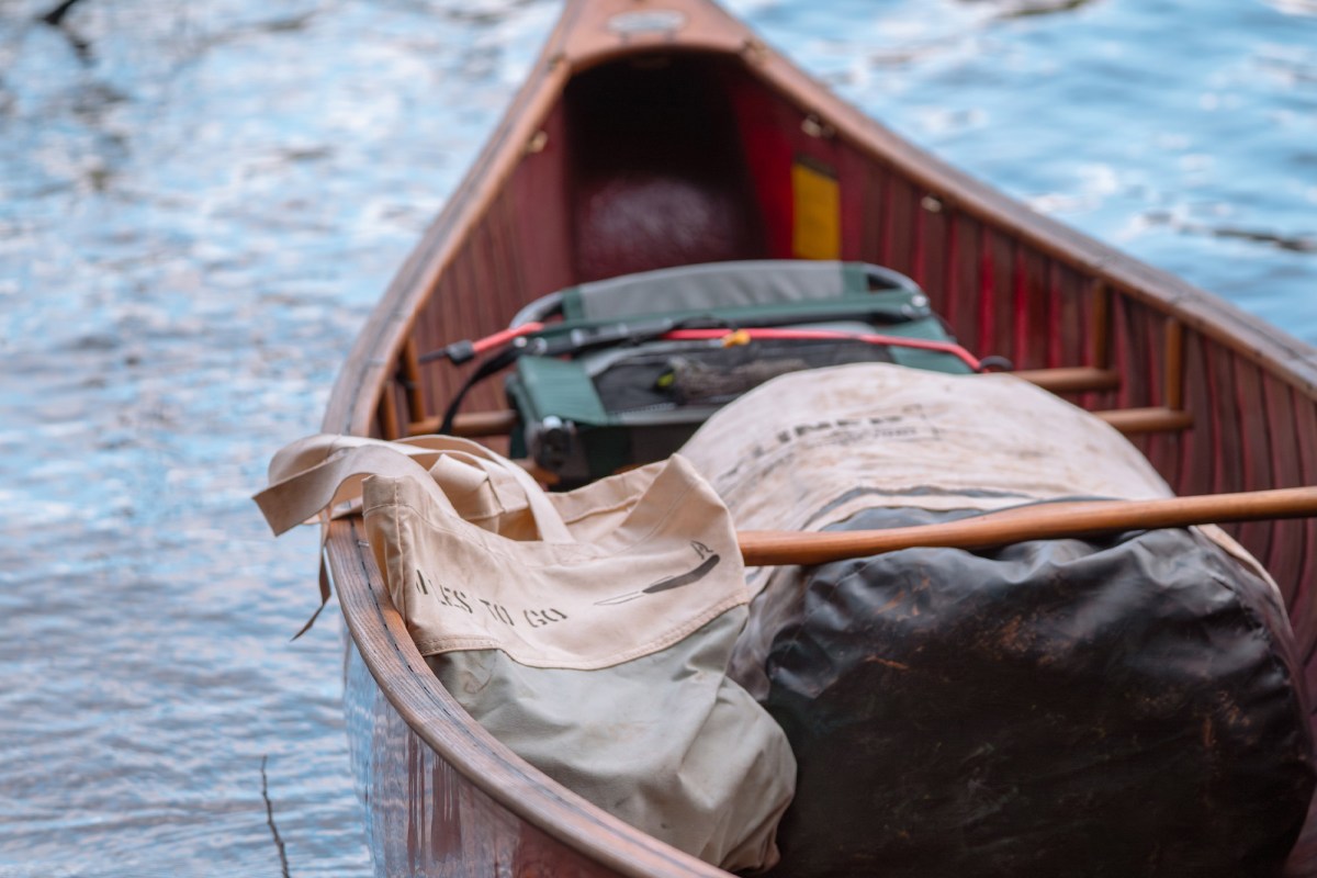 Canvas tent bag and camping gear loaded into a canoe on the water