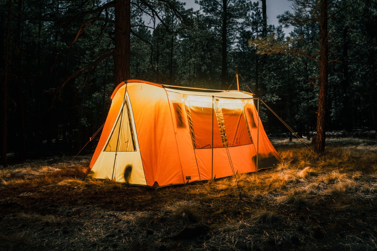 Springbar Skyliner hot tent glowing at night in a wooded campsite with a stove pipe