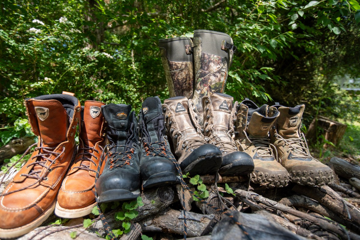 Different boots on a wood pile in a hunting camp.