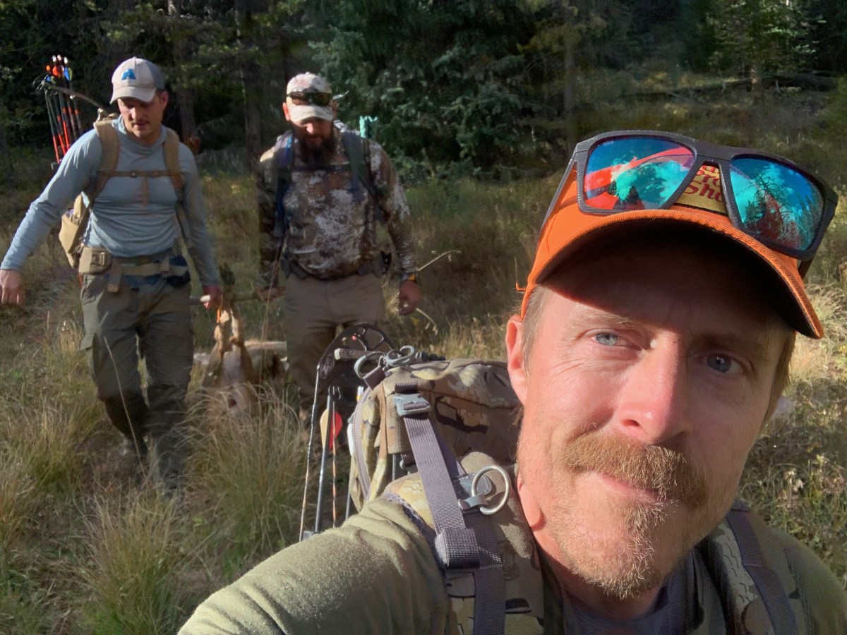 Three men drag a deer out of the woods while hunting