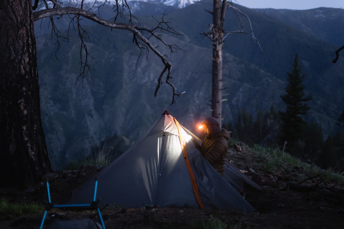 A camper uses the Strike 1800 headlamp while setting up a tent near the mountains