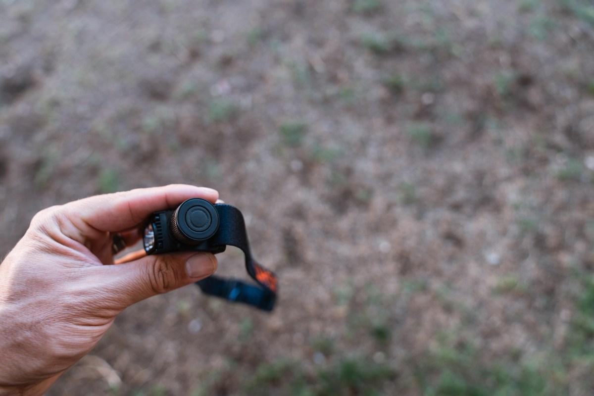 A hand holds the Strike 1800 headlamp with the front button visible