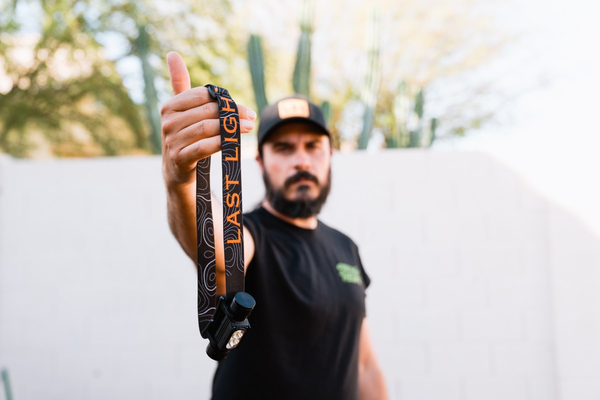 A person holds the Strike 1800 headlamp by its branded strap