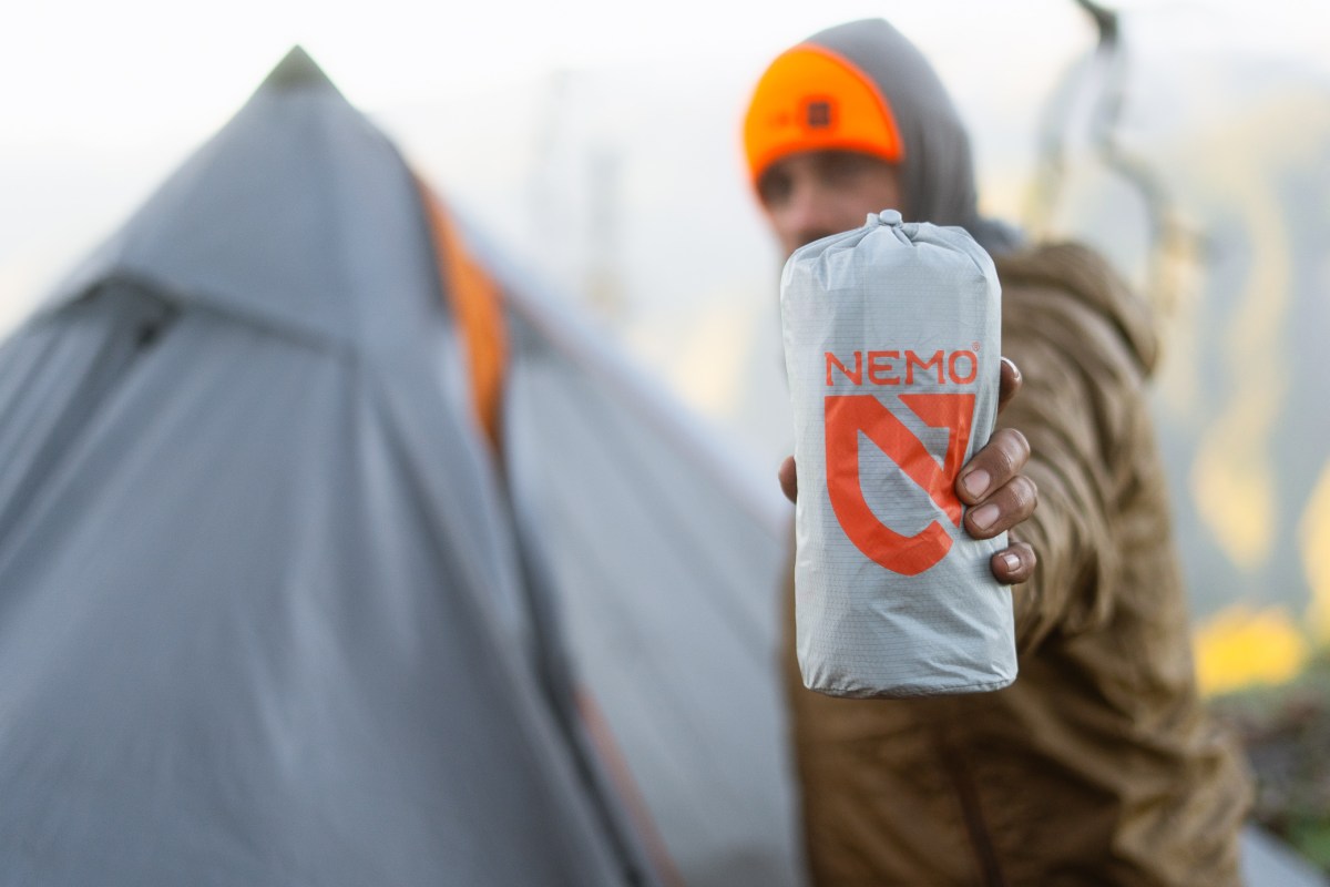 Packed NEMO Tensor sleeping pad held in its stuff sack beside a tent