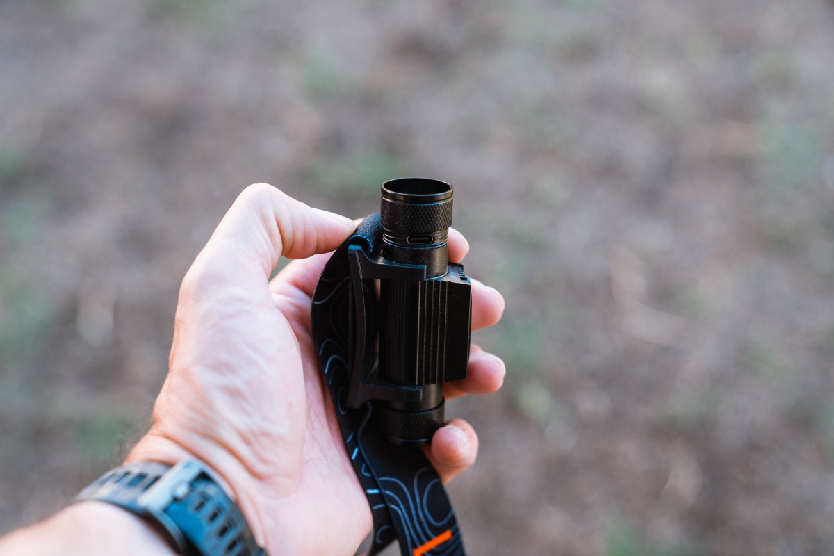 A hand holds the Last Light Strike 1800 Headlamp with the body and strap visible