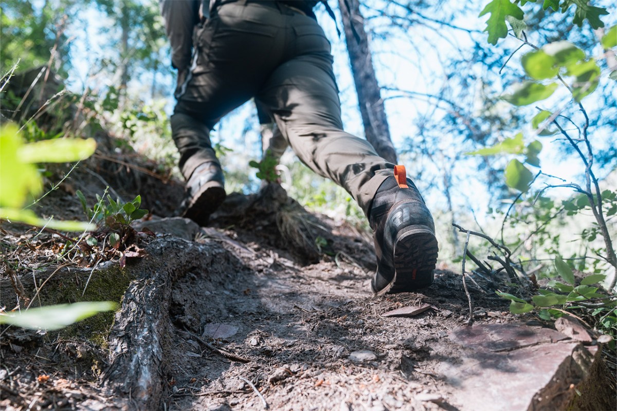 Hiker wearing Crispi boots climbing a steep dirt trail through trees