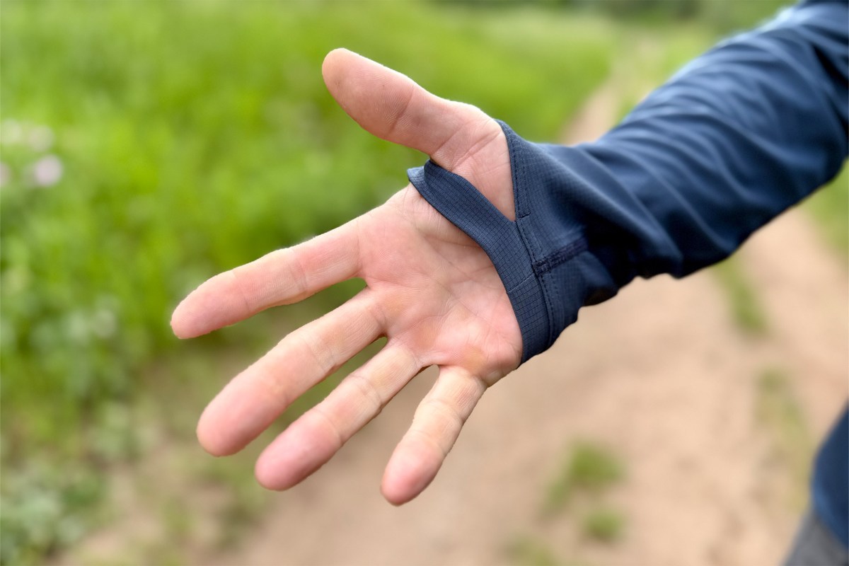 A close-up shows the hoodie thumb loop on one hand