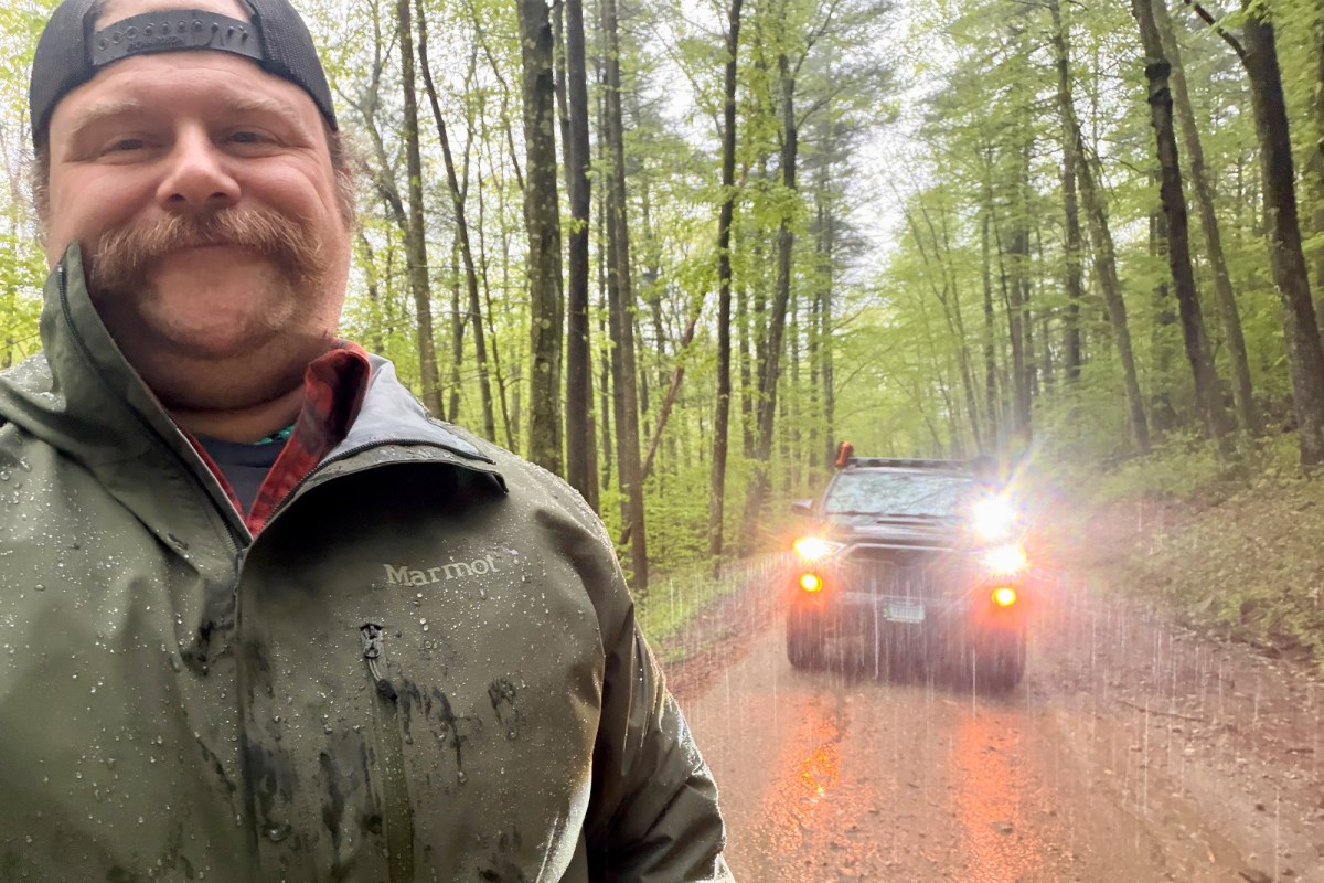 Person wearing the Marmot PreCip Evo Pro jacket in heavy rain on a wooded road