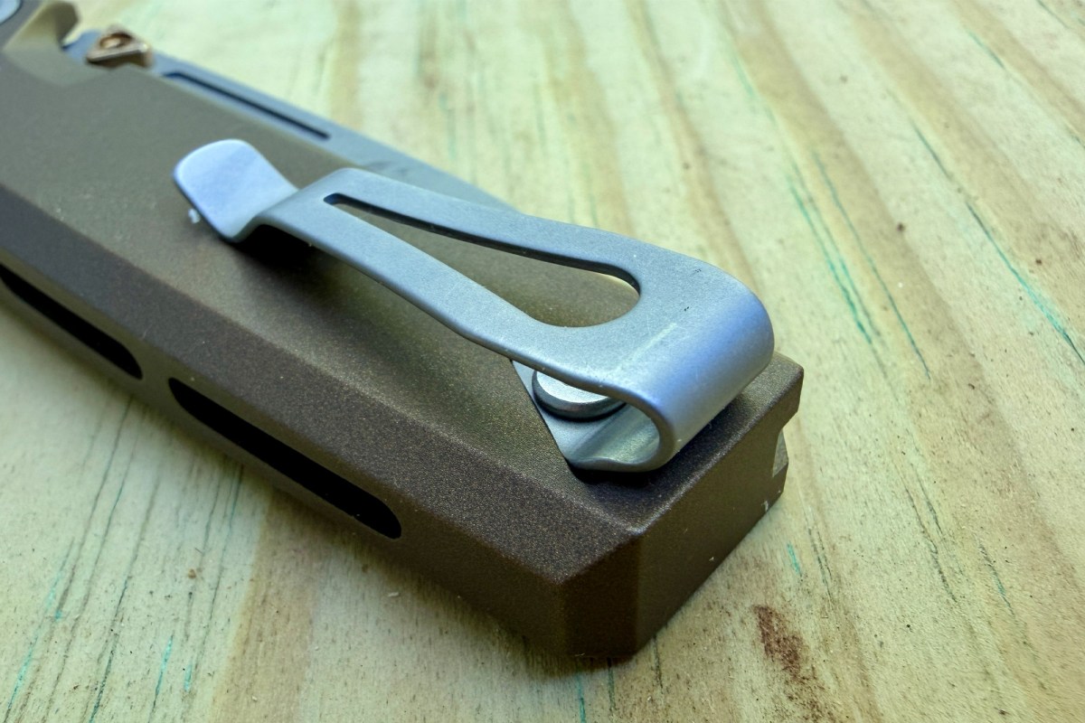 RMX Thumbstud knife pocket clip close-up on a wooden surface