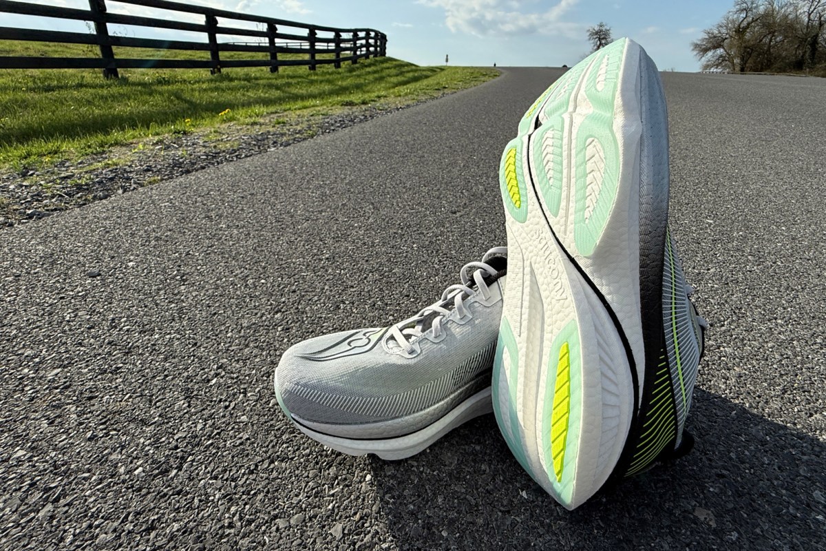 Pair of running shoes on a paved road with one outsole facing the camera