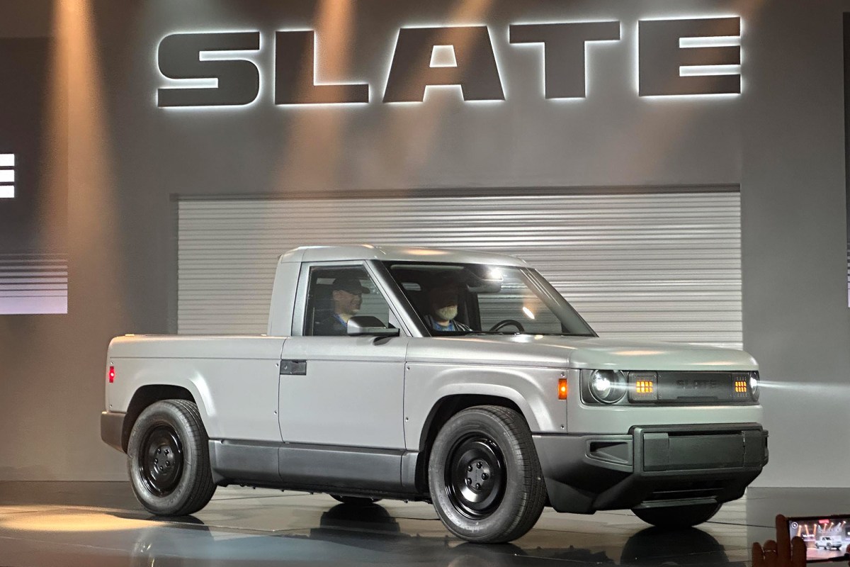 Slate pickup shown from the front at a launch event under an illuminated Slate sign