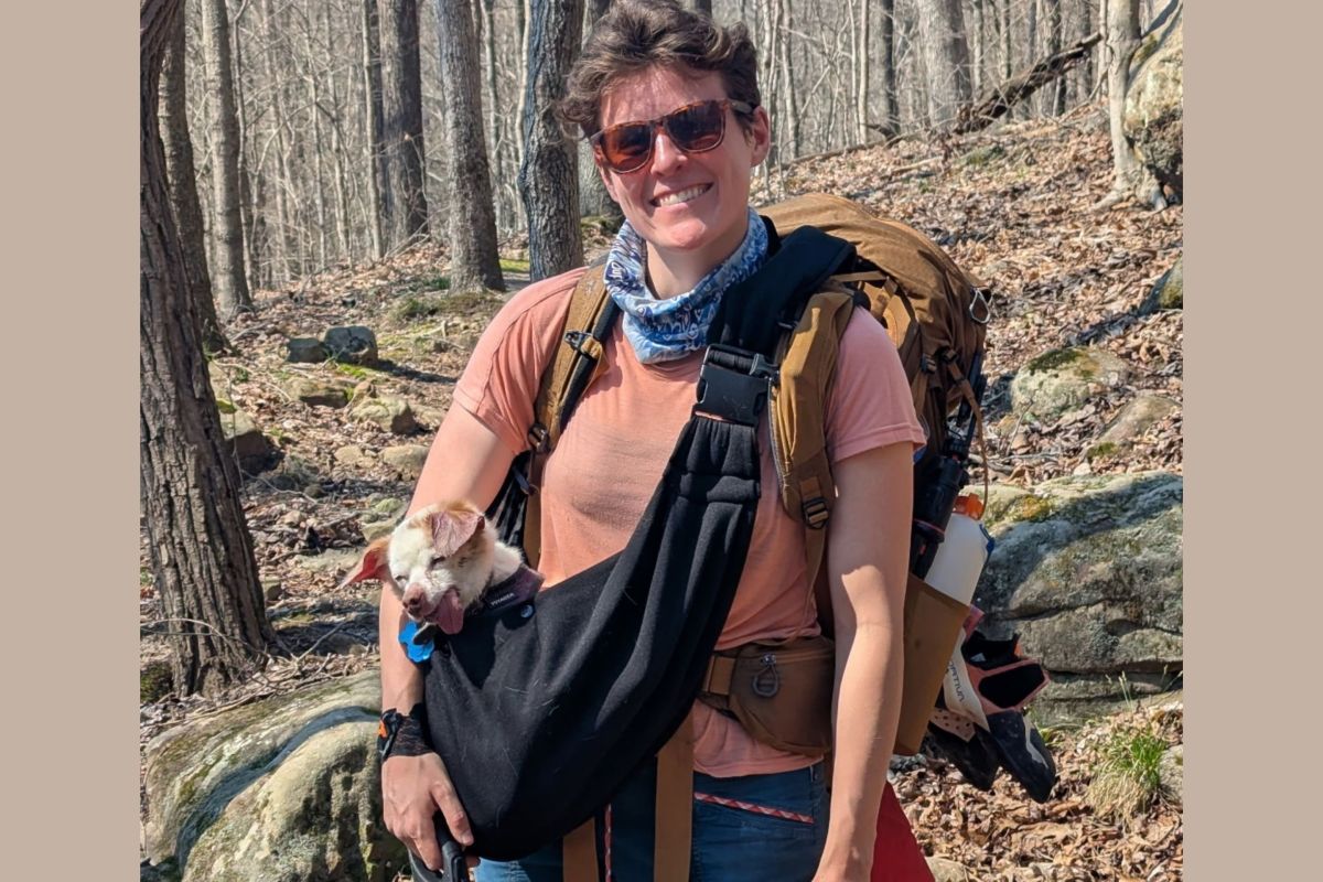 person outdoors with dog in sling