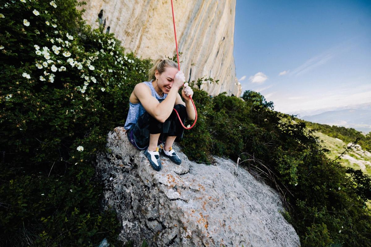 climber holds rope while sitting on rock