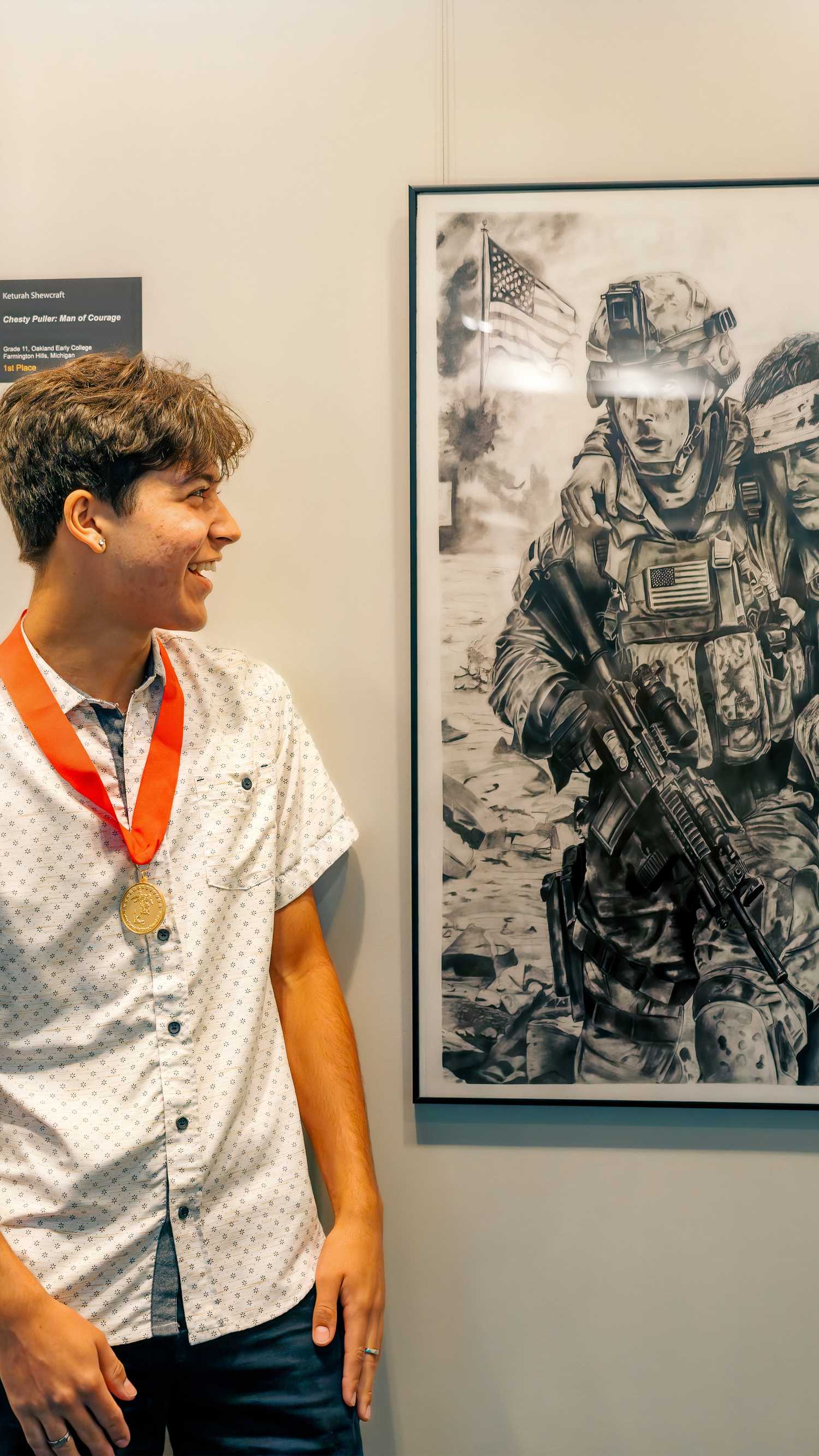 Storm Alho looks at his Best in Show graphite drawing displayed at the National Museum of the Marine Corps.