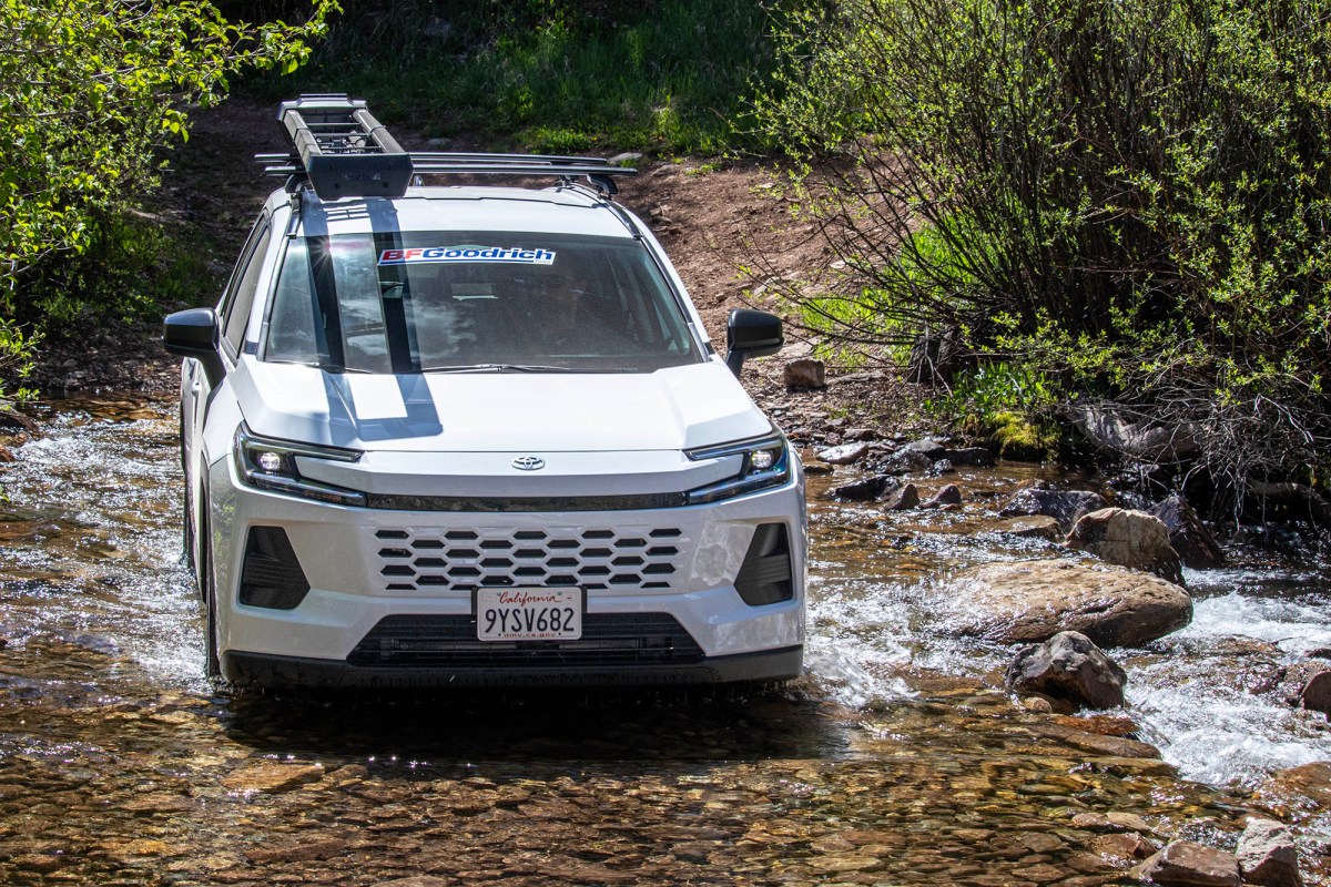 White Toyota RAV4 crossing a rocky stream on a forest trail