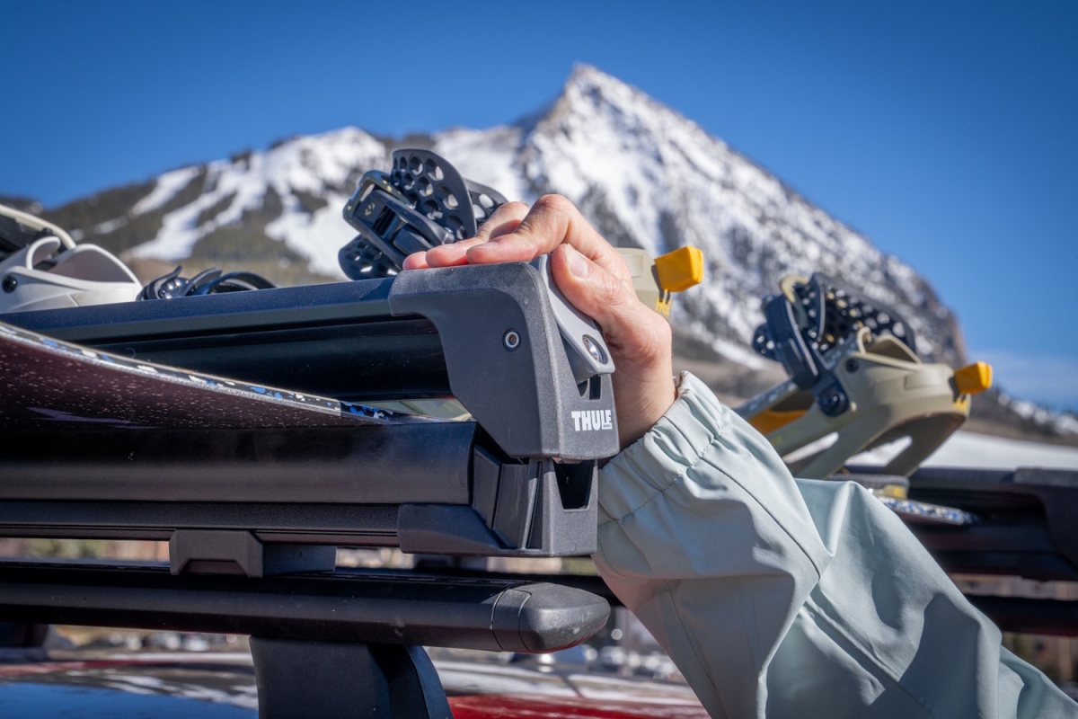 User applying pressure to close the ski rack over thick snowboards