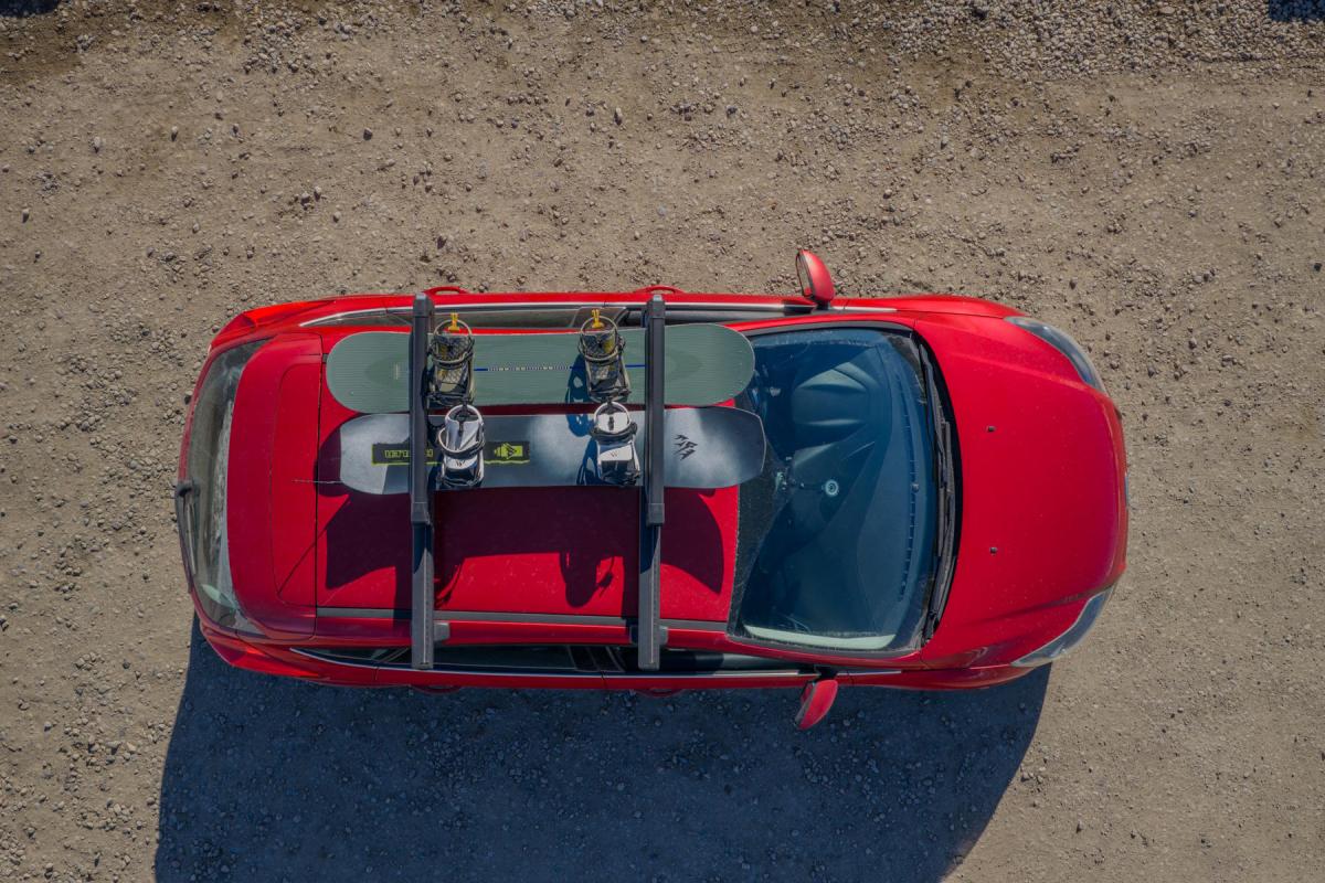 top-down view of two snowboards secured in a Thule roof rack on a red car