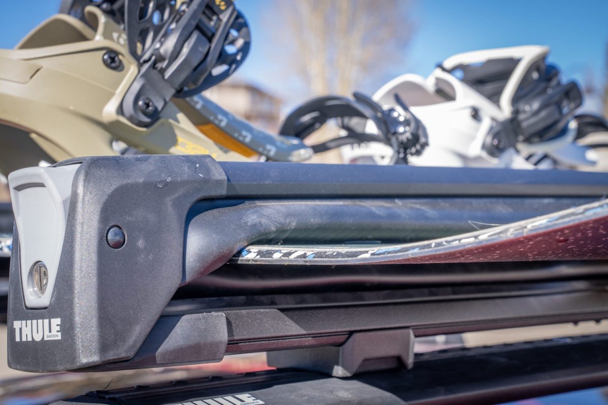 Thule Snowpack ski rack locked onto crossbars with skis and snowboard secured on roof rack