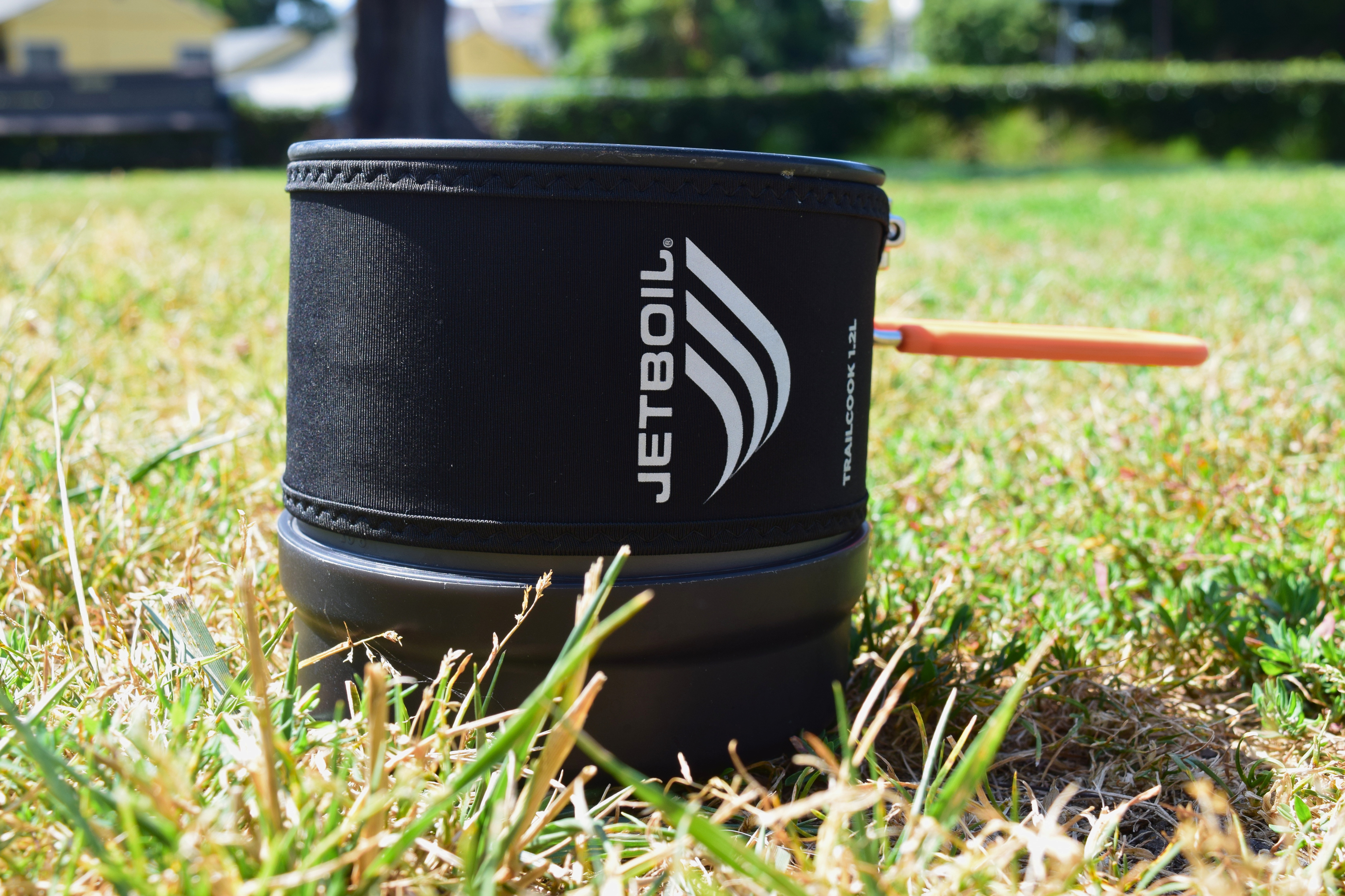Jetboil TrailCook pot sitting in the grass with its orange handle extended