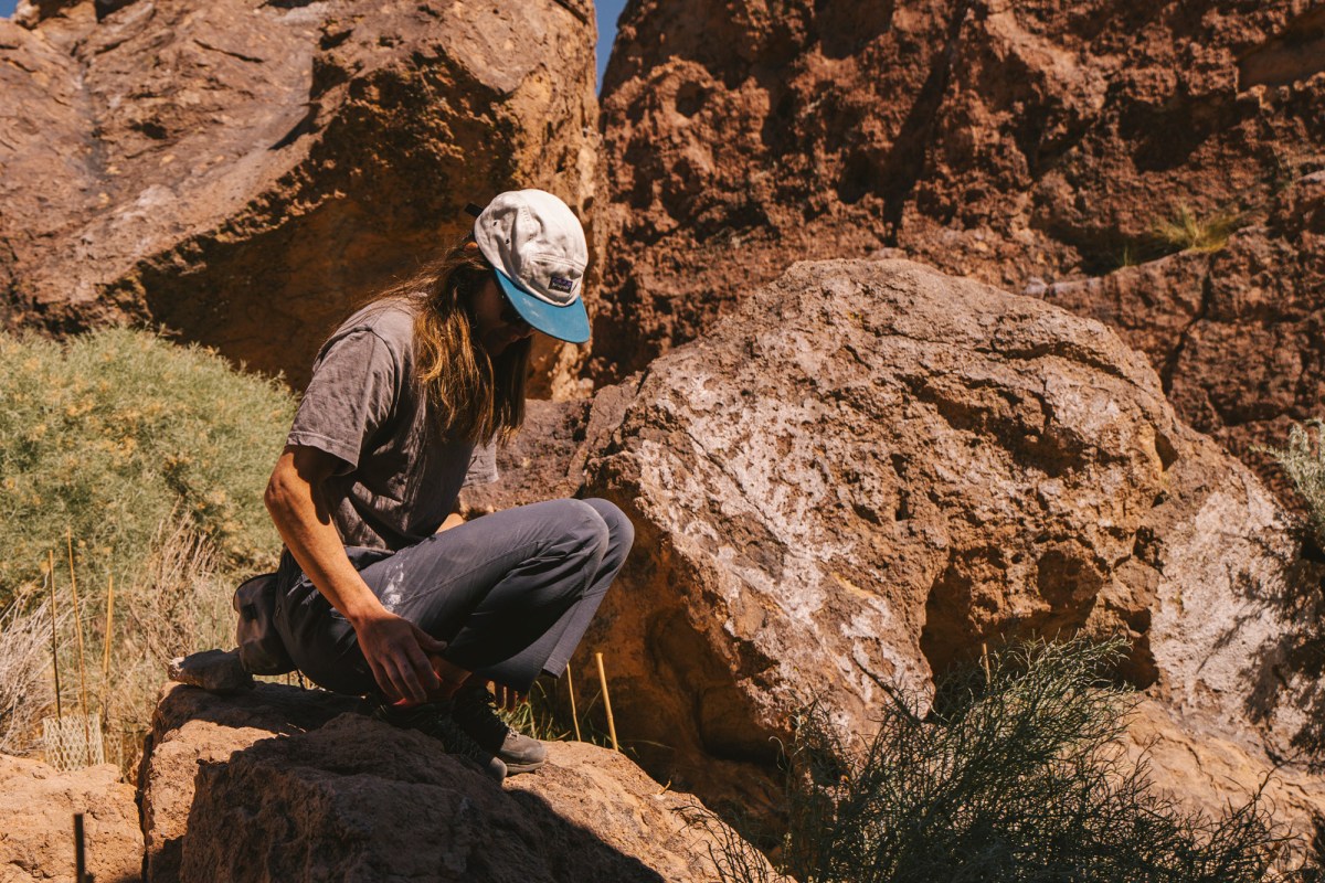 Climber wearing Sequence Pants sits on rocks at a desert crag
