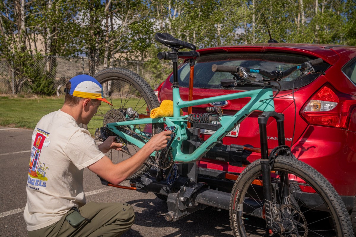 Person working on a mountain bike held by a hitch rack repair stand