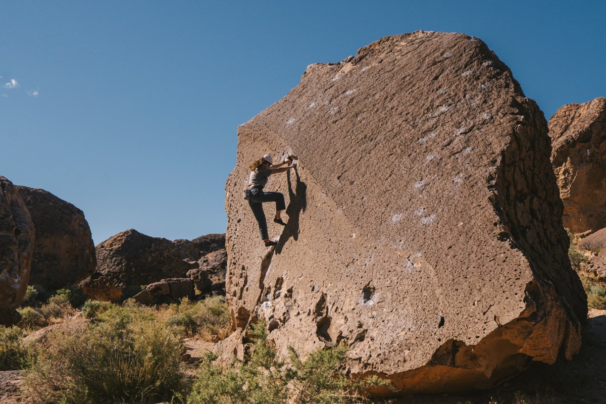 Climber wearing Sequence Pants scales a large desert boulder