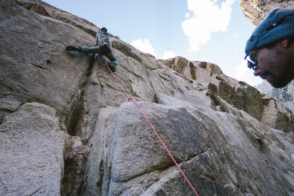 Climber leading a steep granite route with the rope clipped below