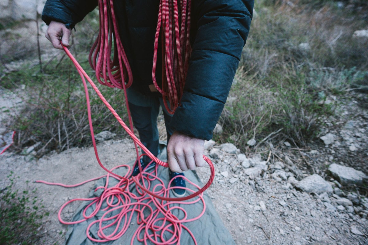 Climber gathering the red rope into coils at the base of the route
