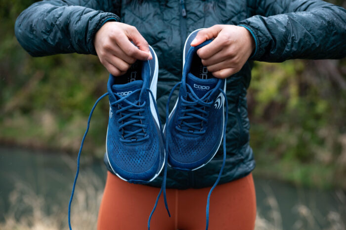 Women holding up Trail Running Shoes