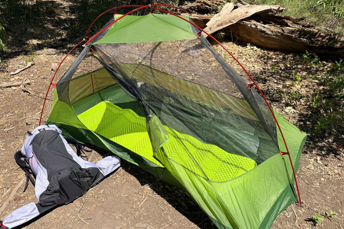 Exped Cassira Two-Person Tent pitched in a wooded area with the mesh door open and a green sleeping pad inside