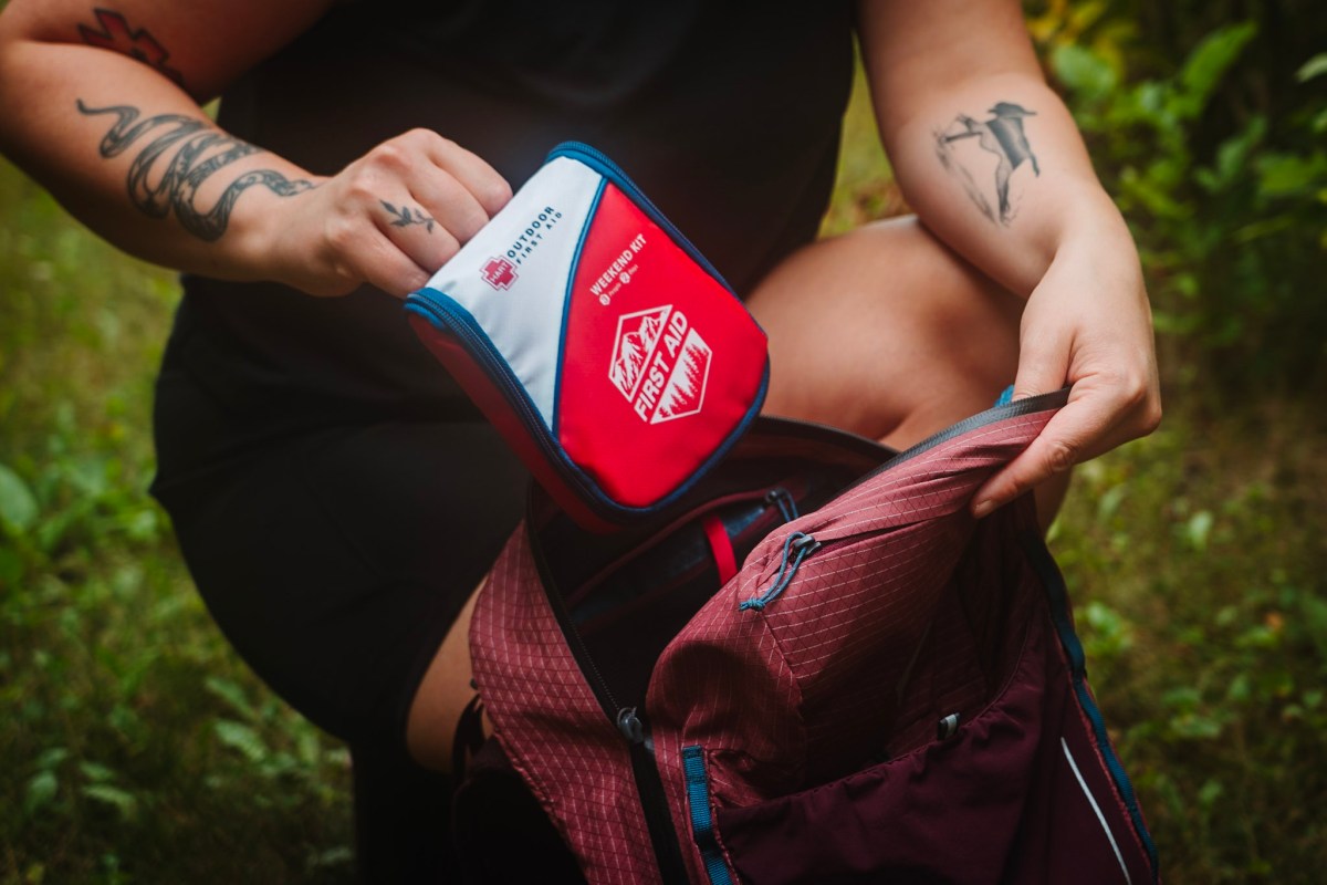 Hiker placing a HART first aid kit into an open backpack