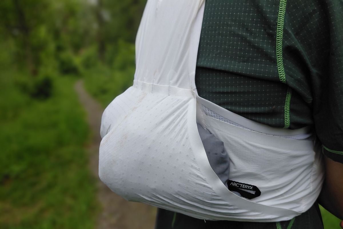 Side view of the LF 5L Running Vest with a jacket packed into the stretch pocket