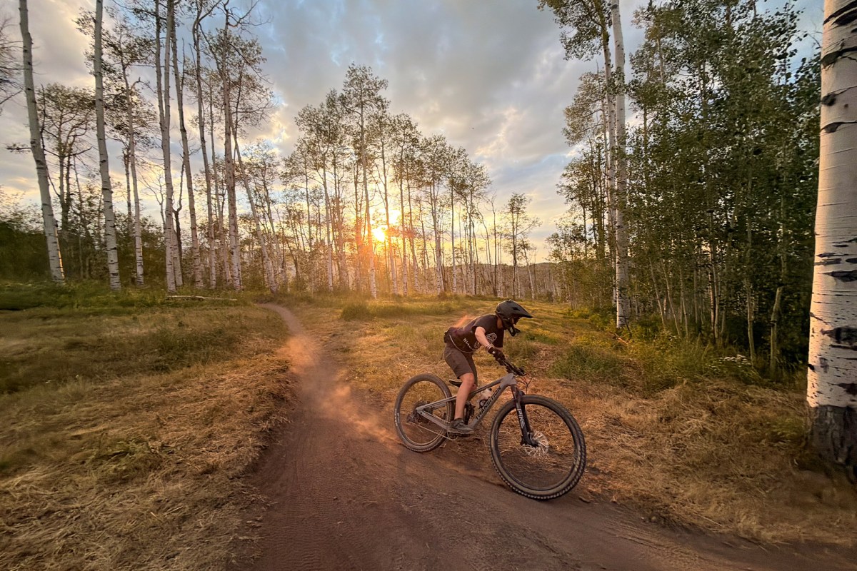 Mountain biker wearing Crankbrothers flat shoes on a forest trail at sunset