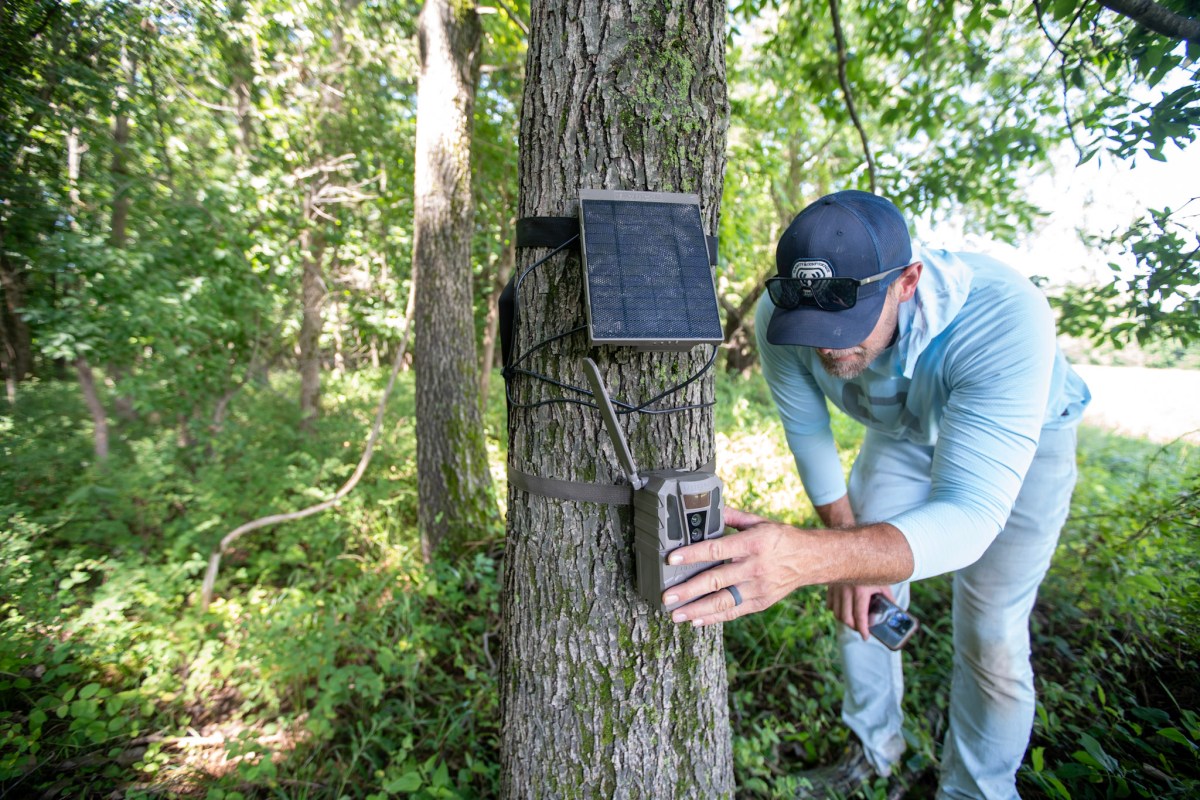 A man setting up the TACTACAM REVEAL 4.0 with a solar panel attached to it.