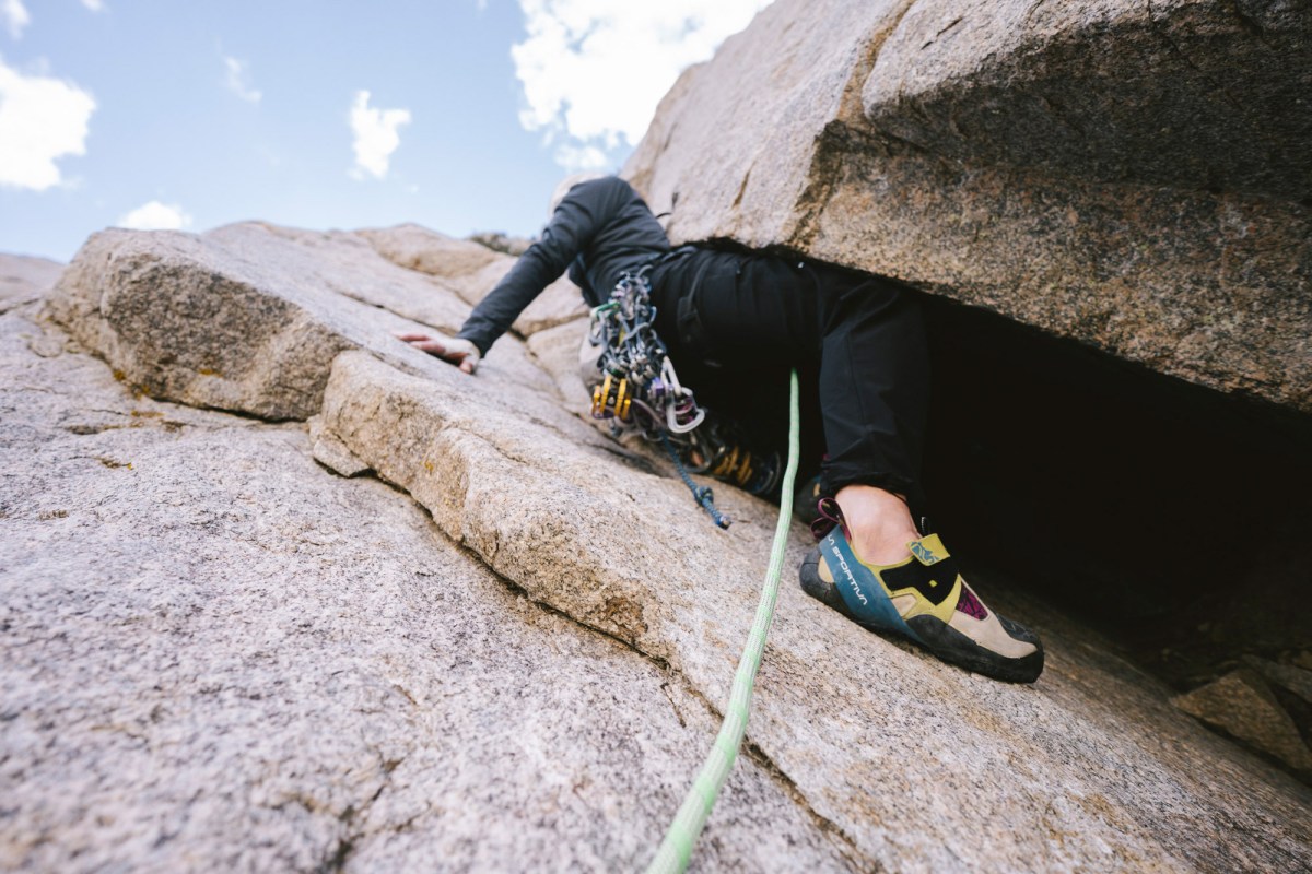 Climber wearing Skwama shoes while moving through a granite crack with a rope below