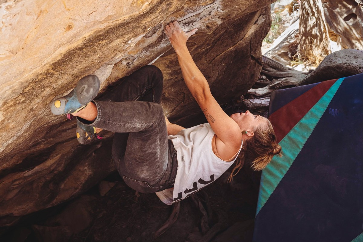 Climber using Skwama shoes on an overhanging boulder above a crash pad