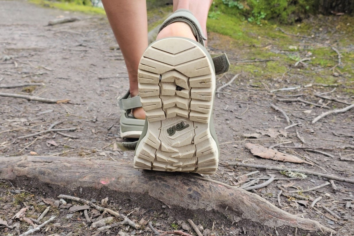 Close up of the Teva sandal outsole showing the tread while stepping over a tree root
