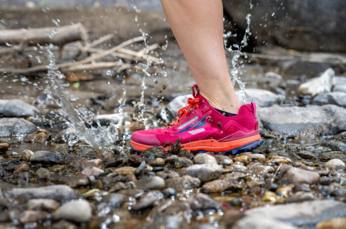 Close up of splashing through a creek in trail running shoes