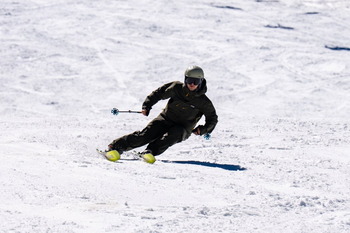 A skier in olive green gear carving a turn on Rossignol Soul 102 skis