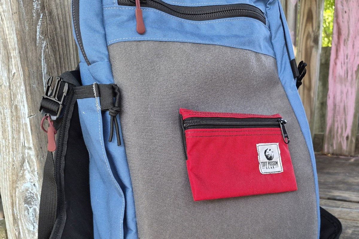 Red zippered pouch attached to the Hill People Gear Commuter front panel