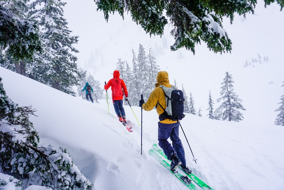 three gearjunkie testers backcountry ski in washington state while wearing bright colored hardshell jackets