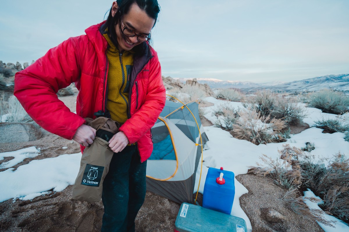 a camper stuffs the helinox ground chair into its stuff sack for storage