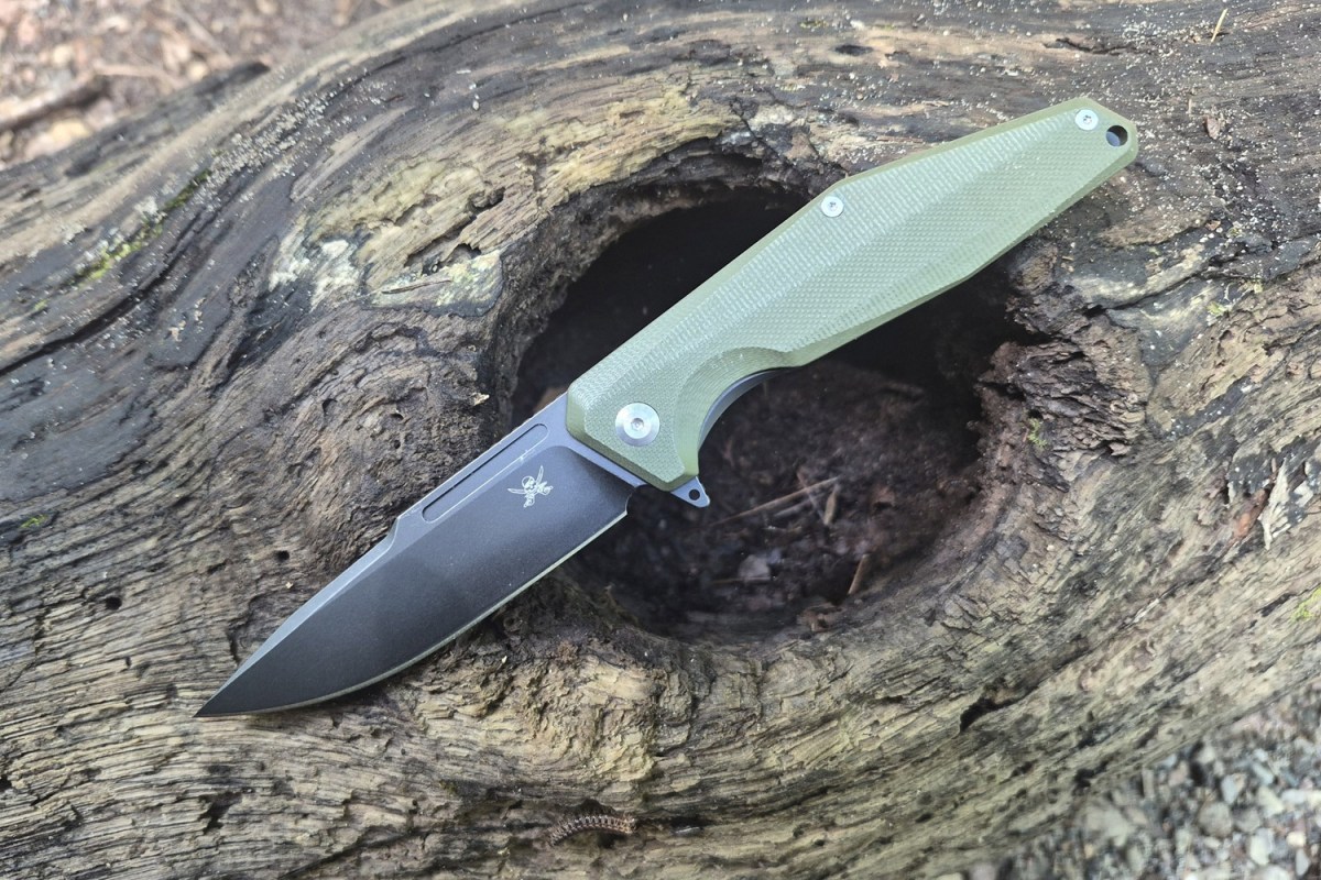 Open Iron Jaw knife resting across a hollow weathered log