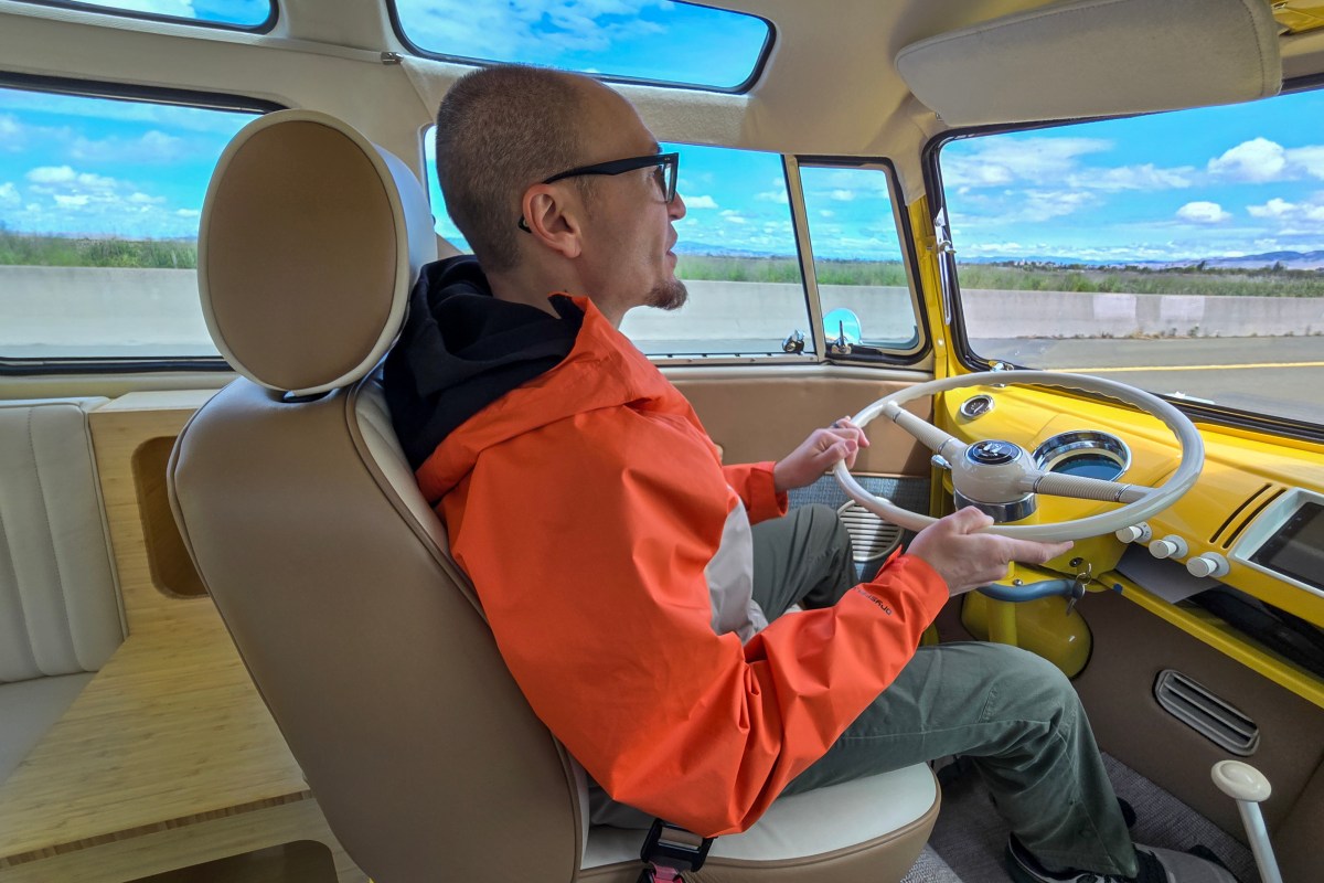 A man in an orange jacket drives the Kindred Motorworks T2 bus