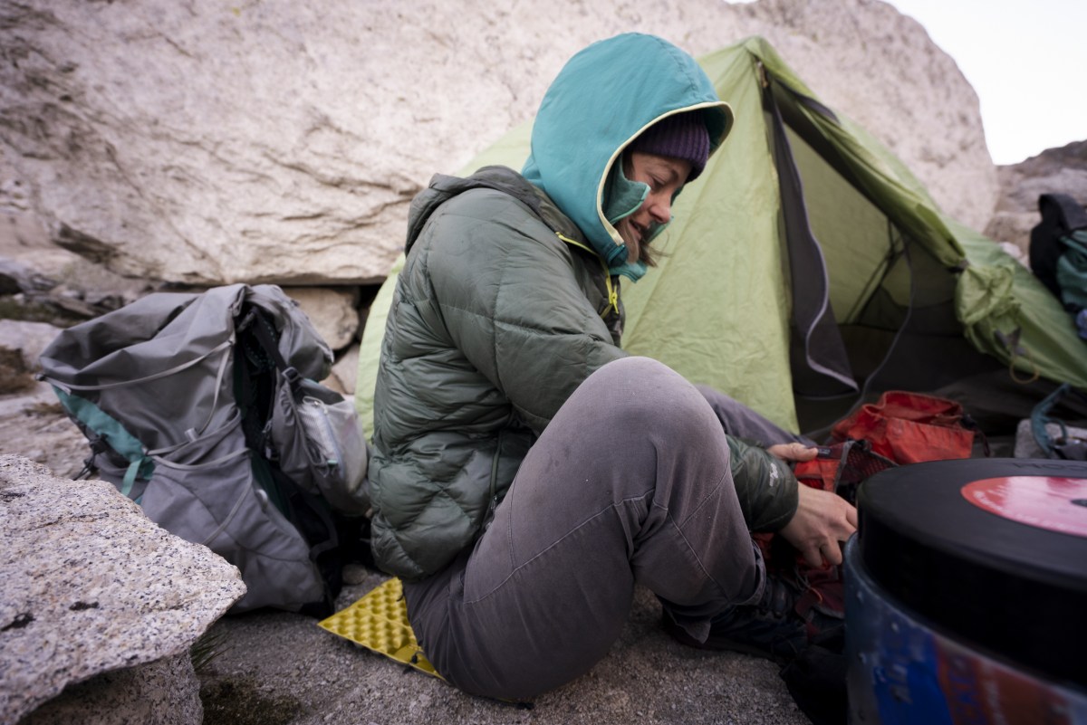 a backpacker sits on a therm-a-rest z seat while putting away camp in california