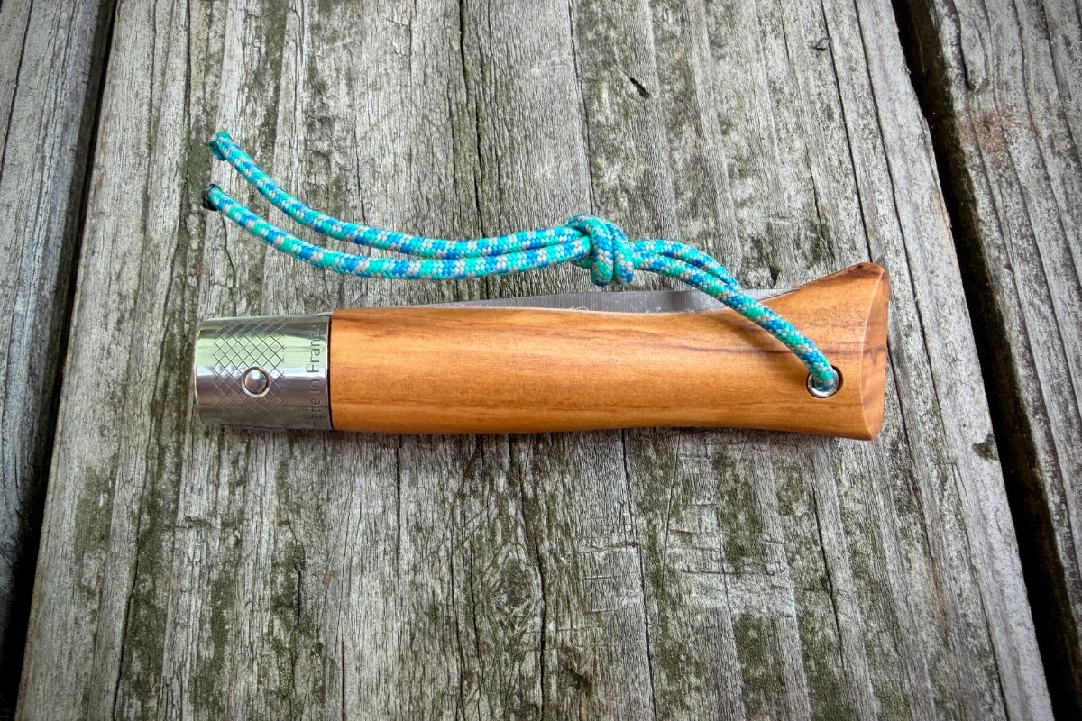 Closed Opinel knife with wooden handle and blue cord lanyard