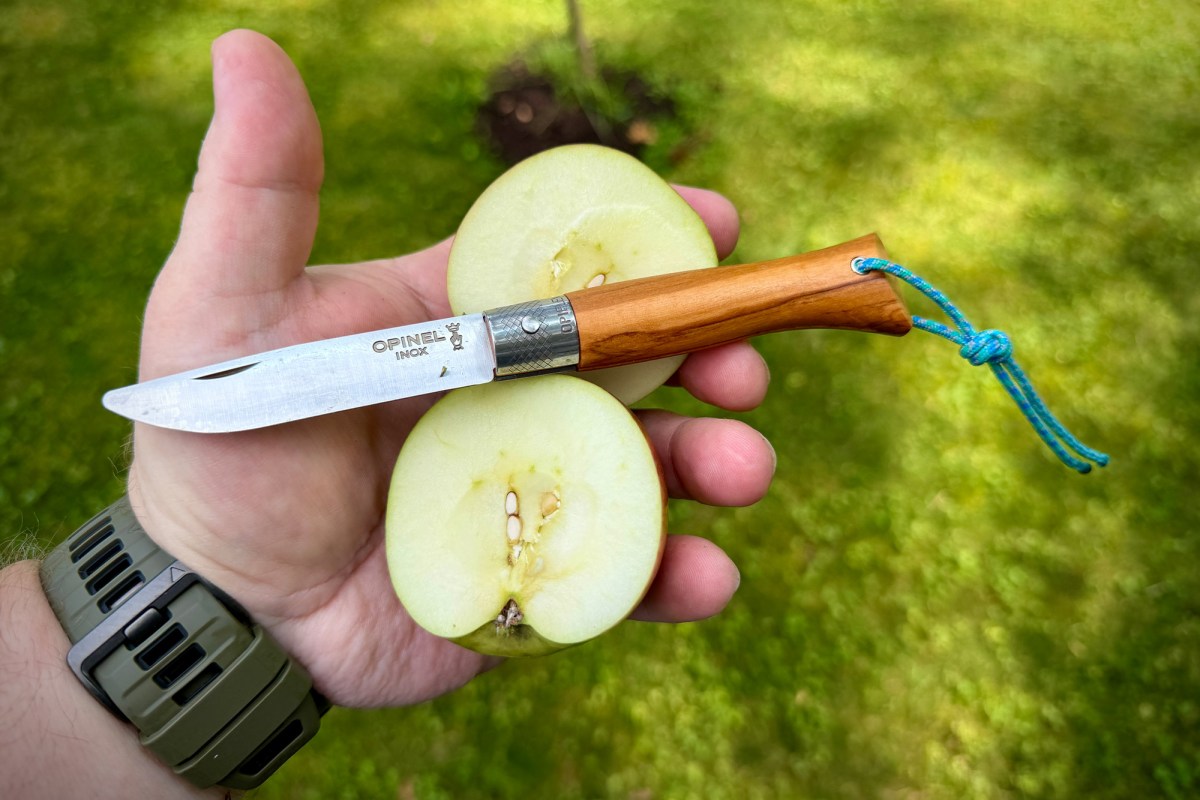Opinel knife held with a freshly sliced apple outdoors