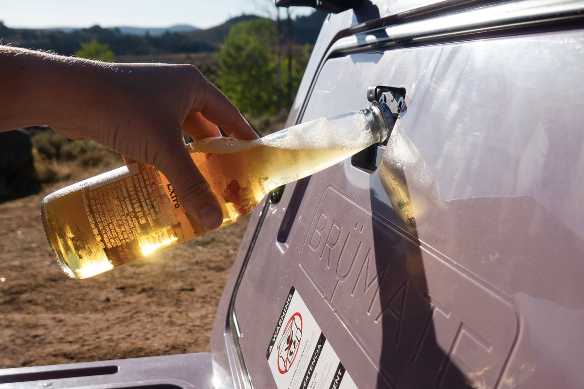 Person using the BrüMate BrüTank bottle opener on a glass bottle