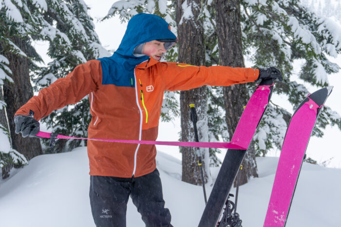 a gearjunkie tester rips splitboard skins while wearing the Ortovox Ortler hardshell jacket